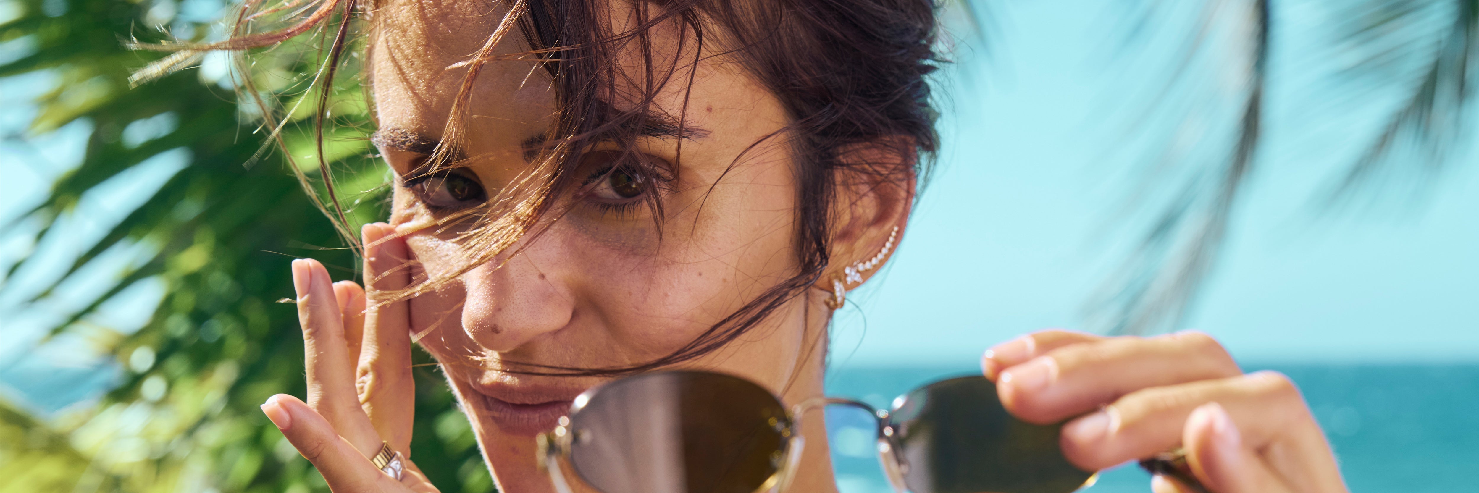 Woman holding sunglasses with a blurred natural background