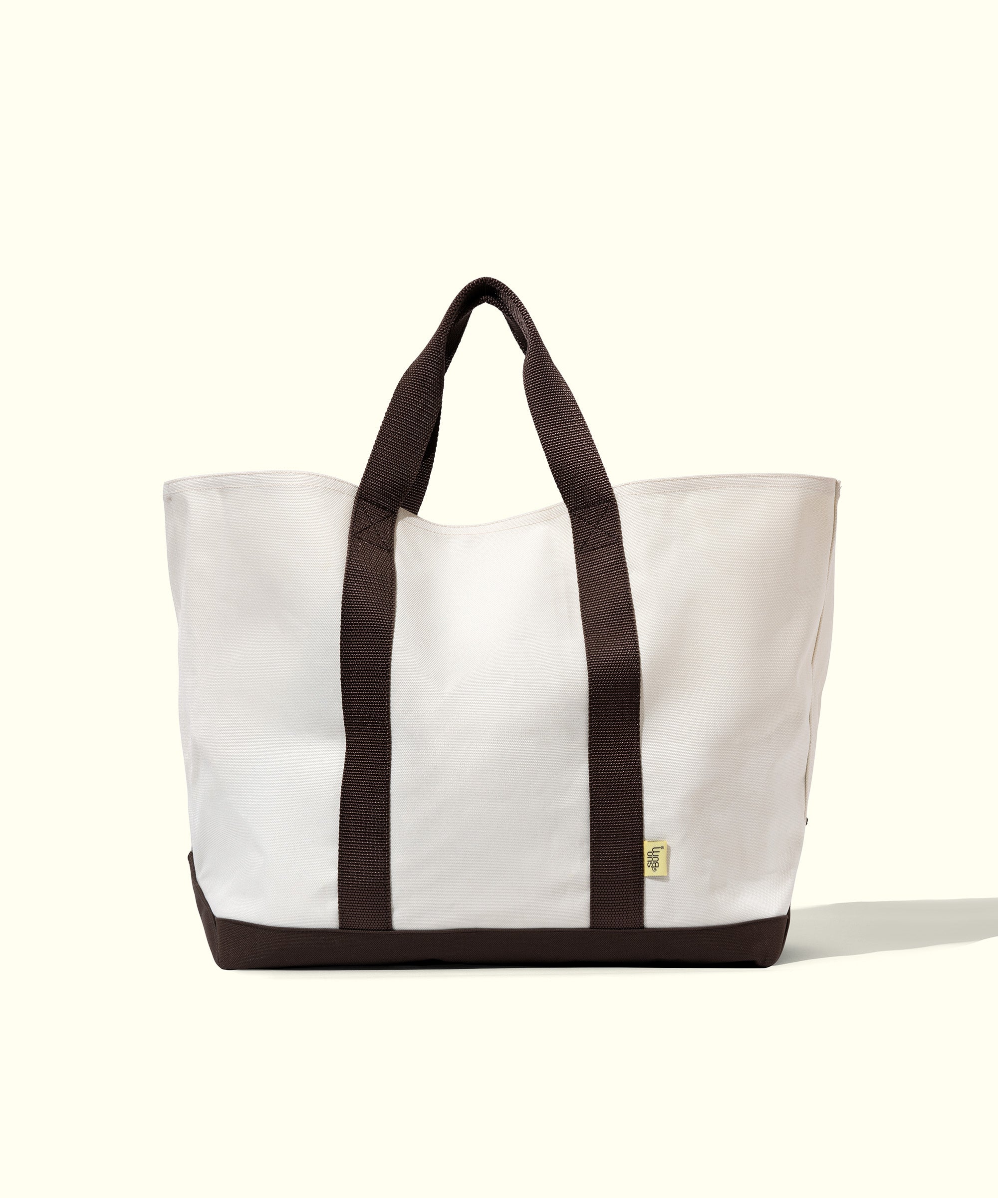 White tote bag with brown handles on a white background