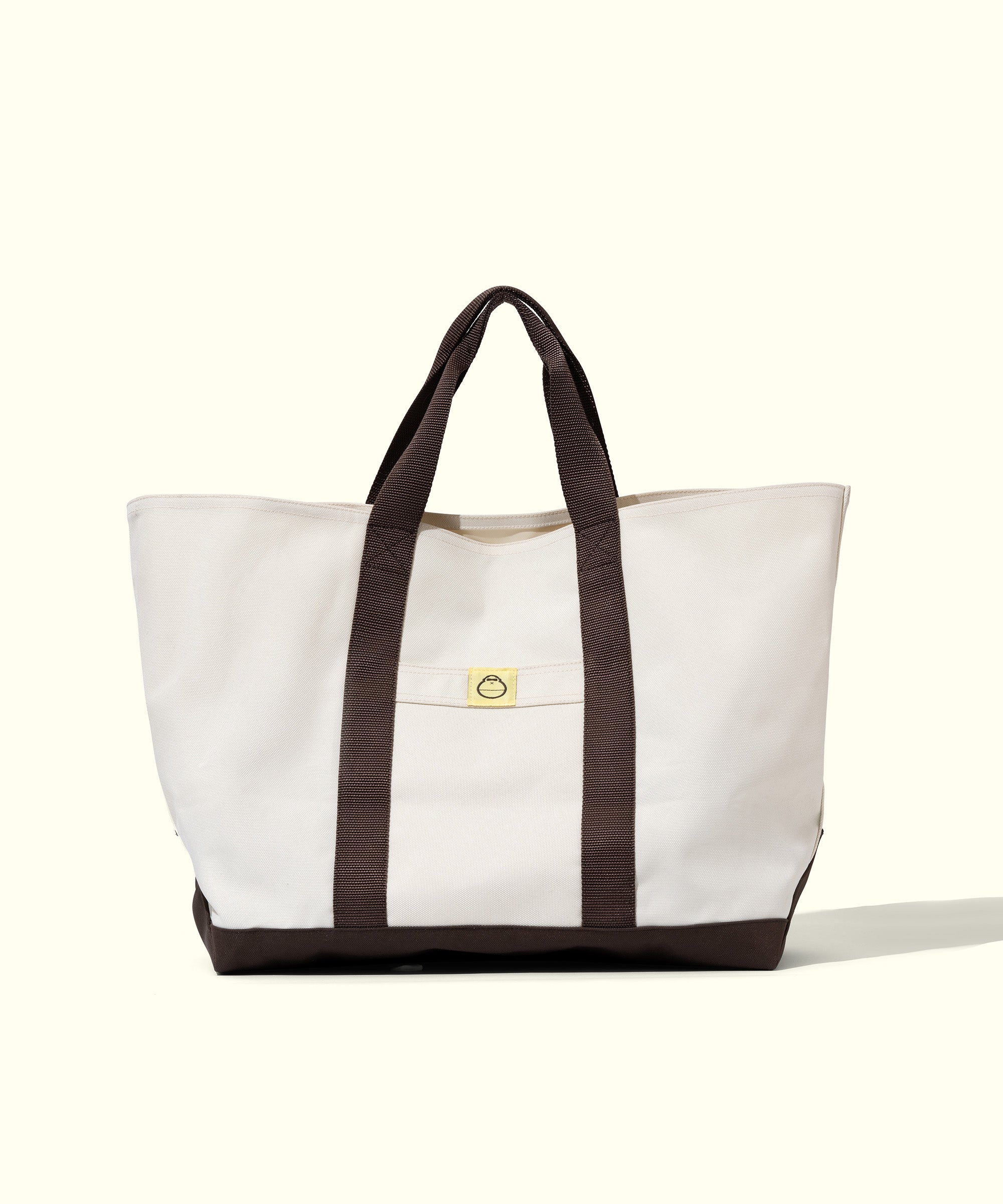White tote bag with brown handles on a white background