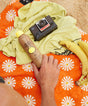 Sunscreen bottle, camera, and bananas on a colorful towel