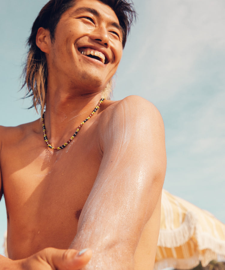 Man with a necklace sitting outdoors with a clear sky background