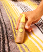 Hand holding a bottle of Sun Bum sunscreen on a striped fabric background