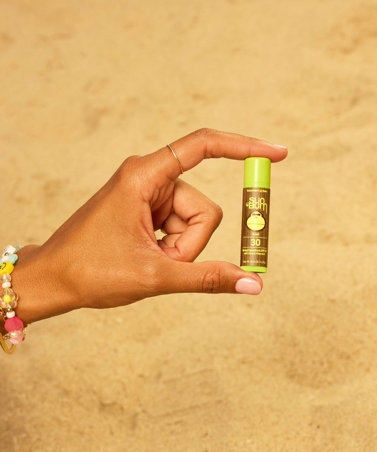 Hand holding a small green bottle with a beige background