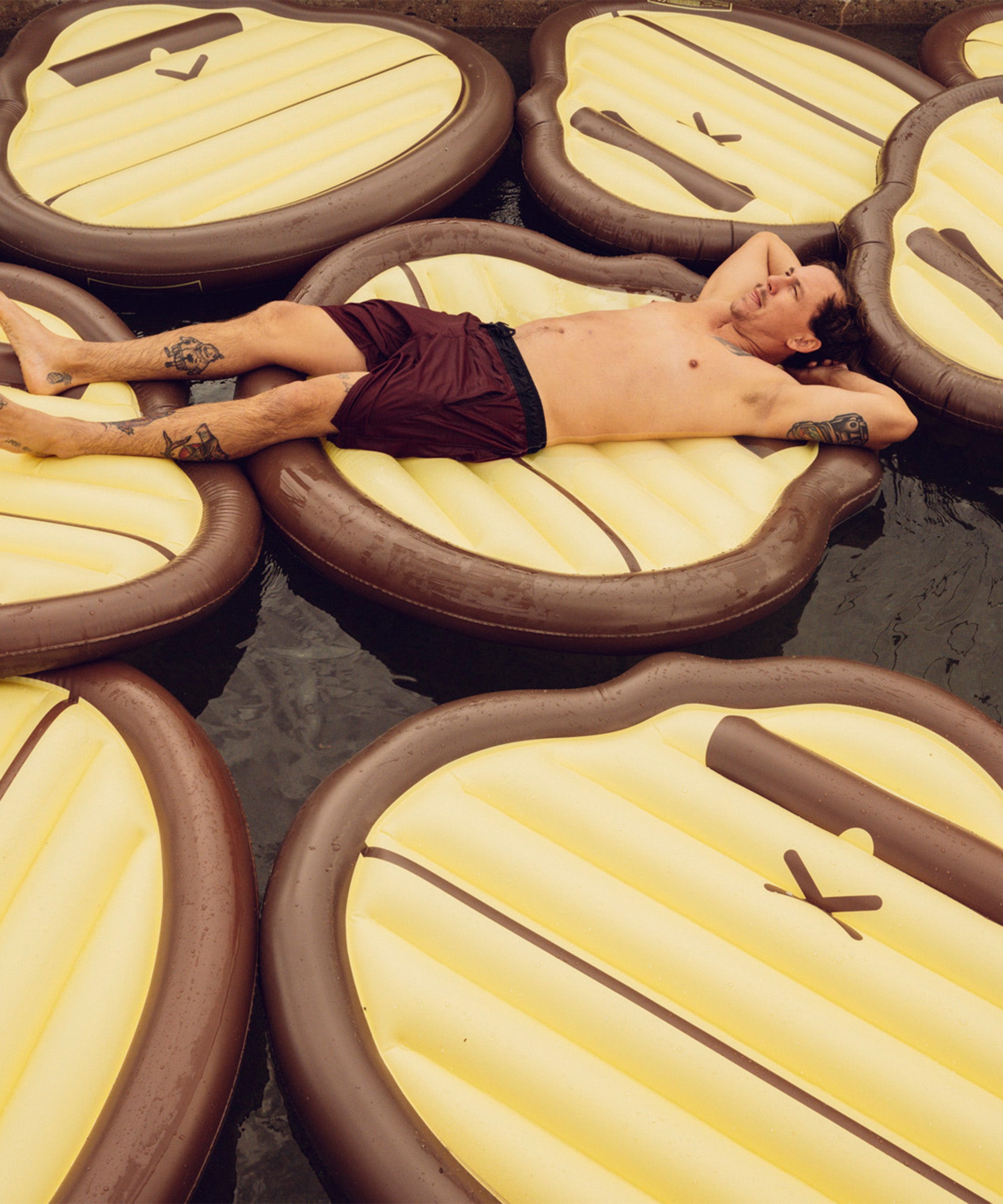 Man lying on a large inflatable mattress with a unique design, surrounded by similar mattresses.