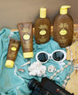 Sun Bum sunscreen bottles and a tube on a towel with sunglasses and beach accessories.