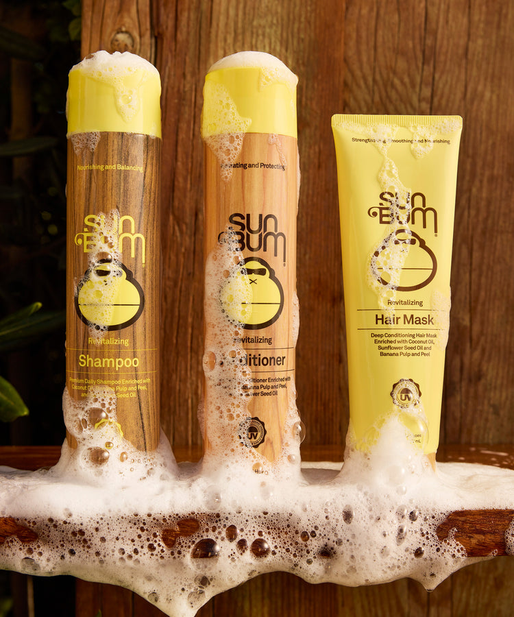 Sun Bum hair care products including shampoo, conditioner, and hair mask on a wooden surface.