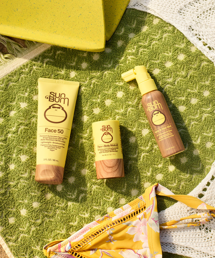 Sun Bum sunscreen products on a green textured surface with a yellow bag.