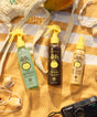 Three Sun Bum sunscreen products on a yellow patterned towel with a camera and seashells.