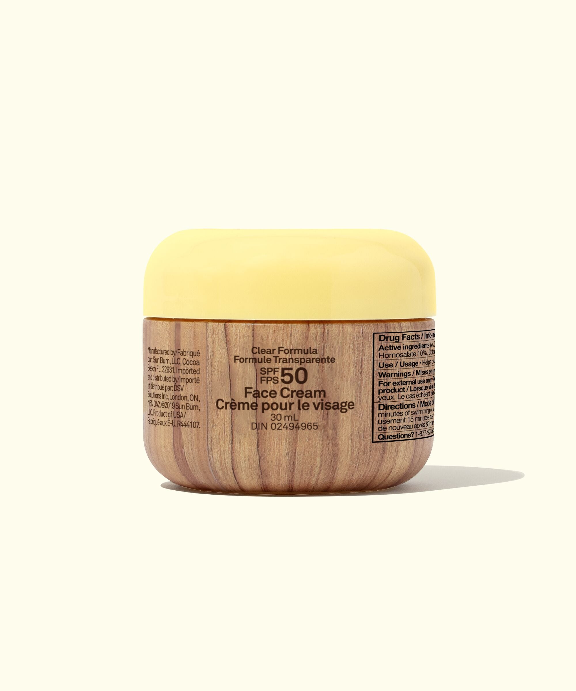 Face cream jar with yellow lid and wooden base on a white background