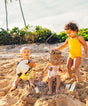 Three children playing in the sand on a beach with palm trees in the background.