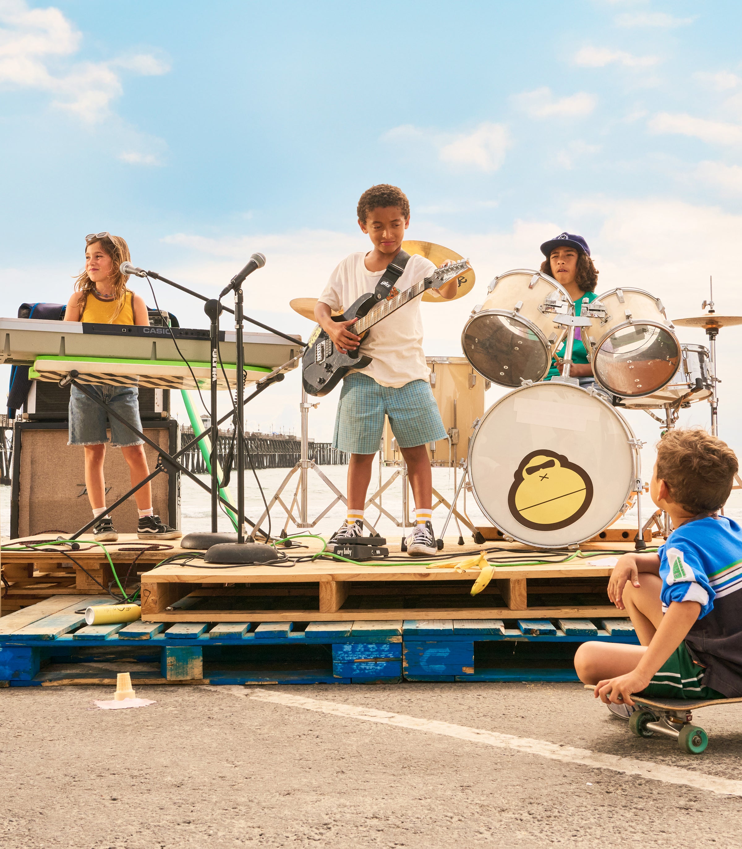 Children playing music on a makeshift stage with pallets and drums.