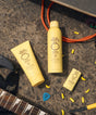 Sun Bum sunscreen products on a textured surface with guitar and other items.