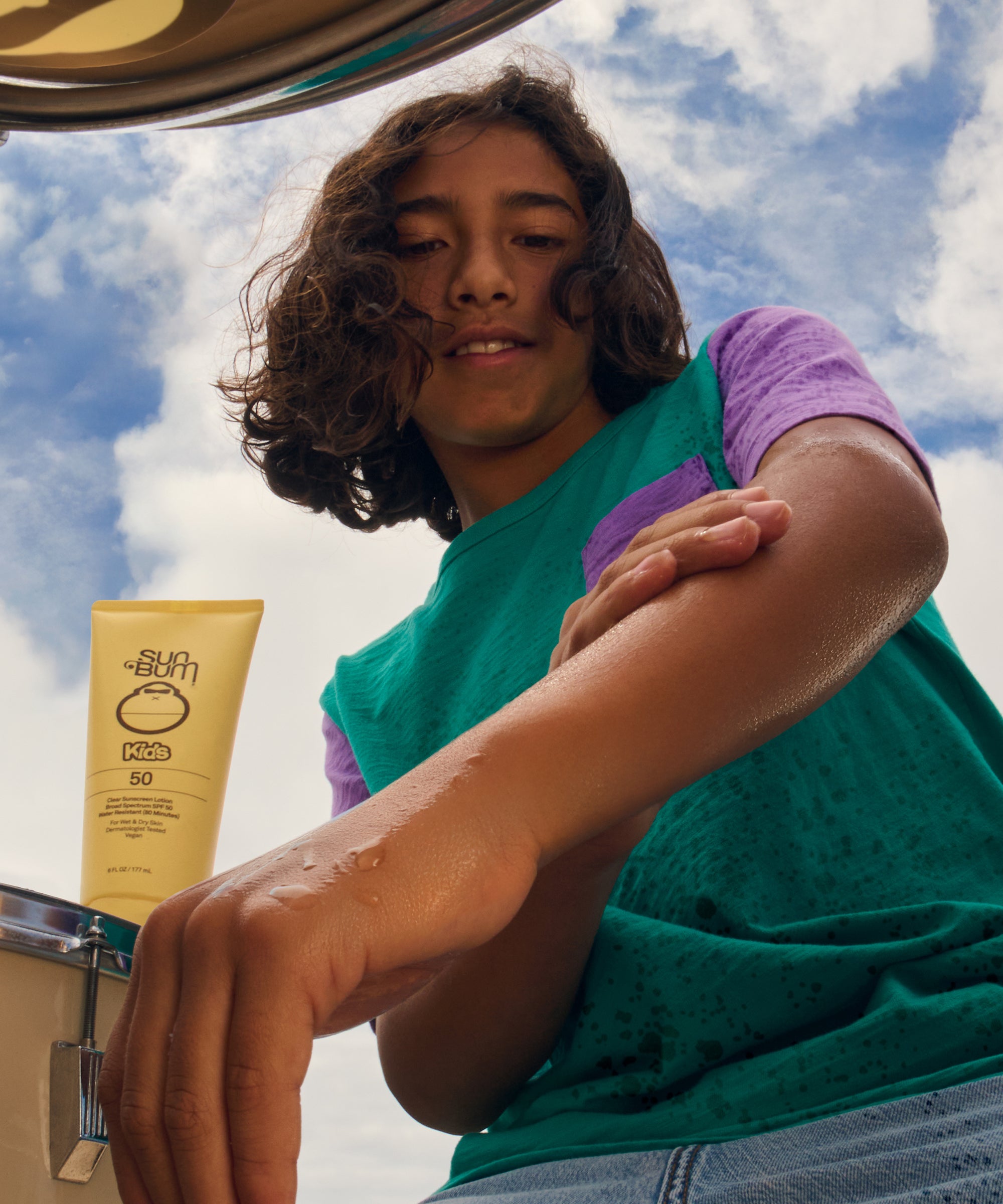 Person with a tube of sunscreen against a blue sky background