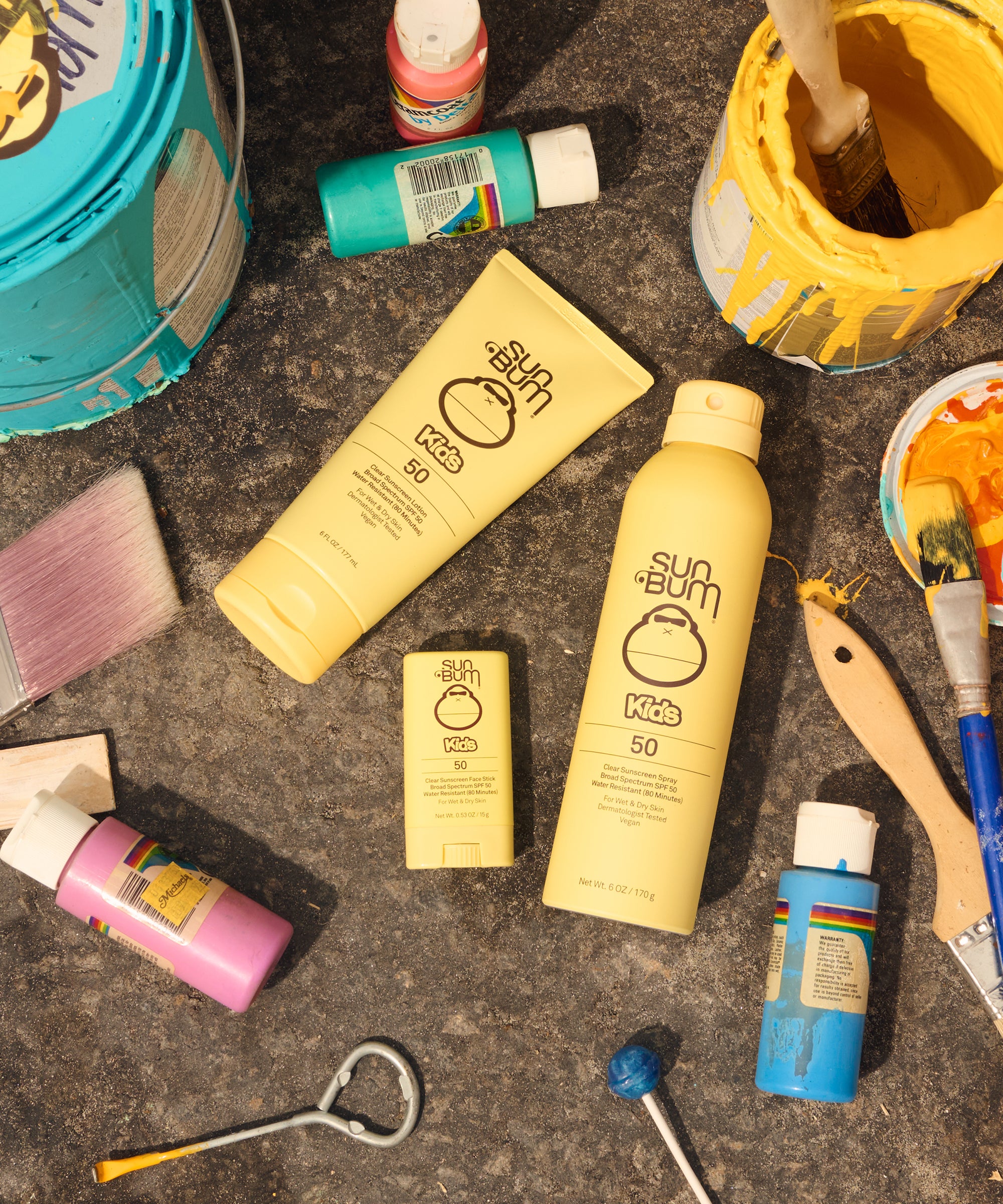 Sun Bum sunscreen products on a textured surface with tools and containers.