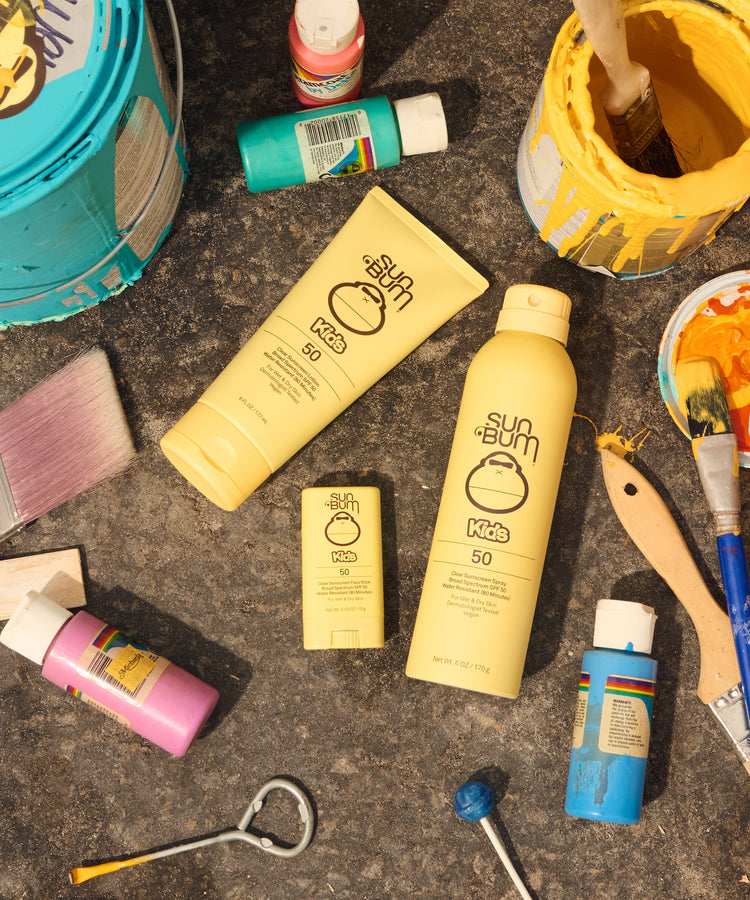 Sun Bum sunscreen products on a textured surface with tools and containers.