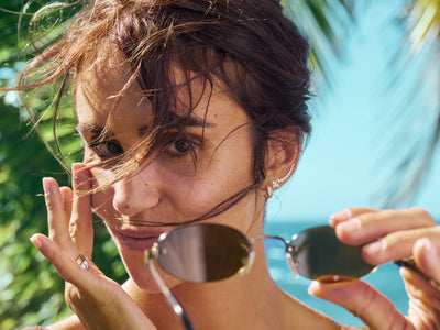 Woman holding sunglasses with a blurred natural background