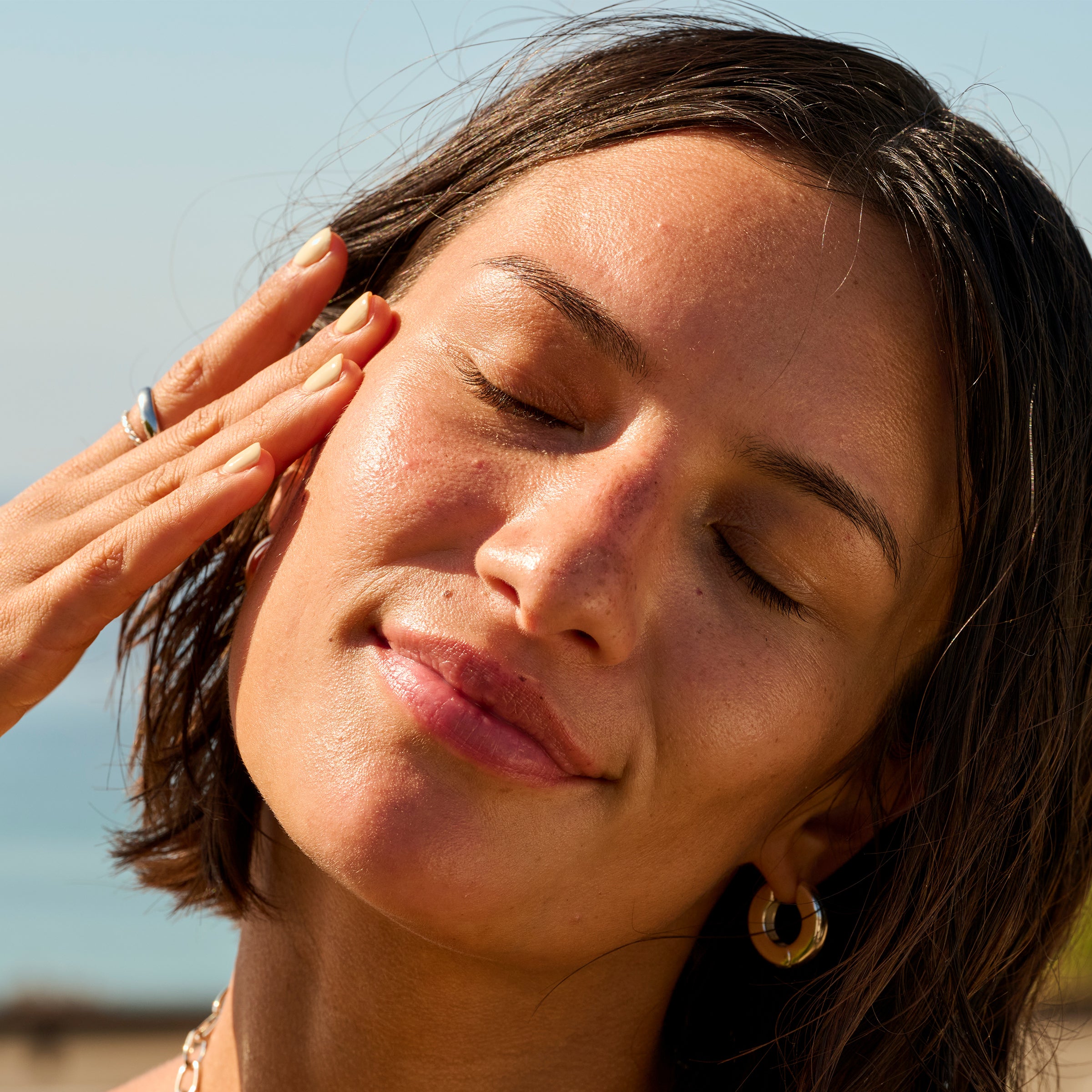 Woman shielding her eyes from the sun with her hand outdoors