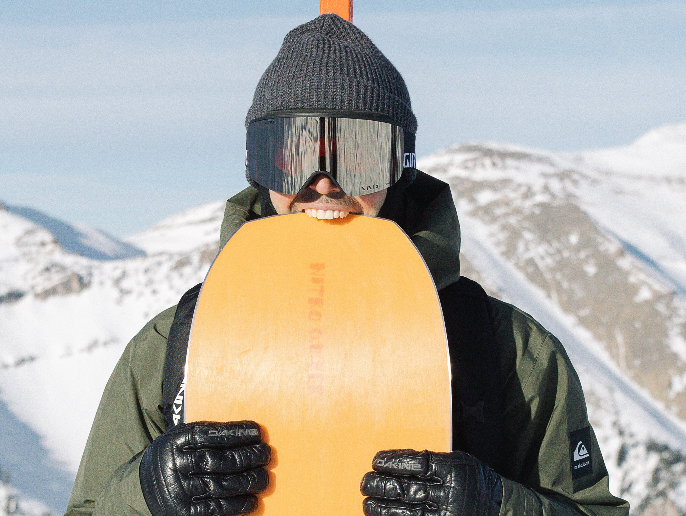 Person holding a snowboard with a mountainous background