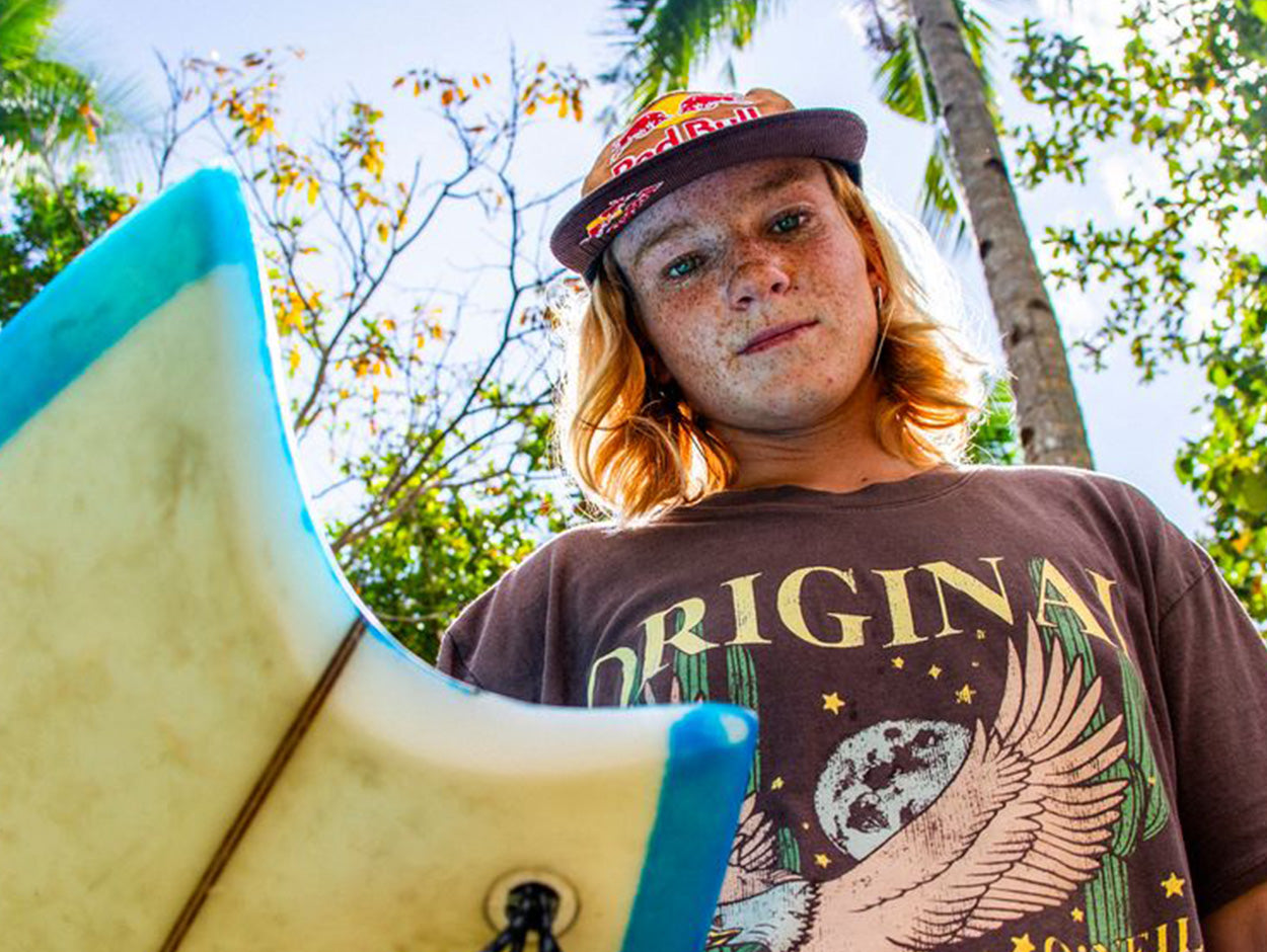 Person holding a surfboard with trees in the background