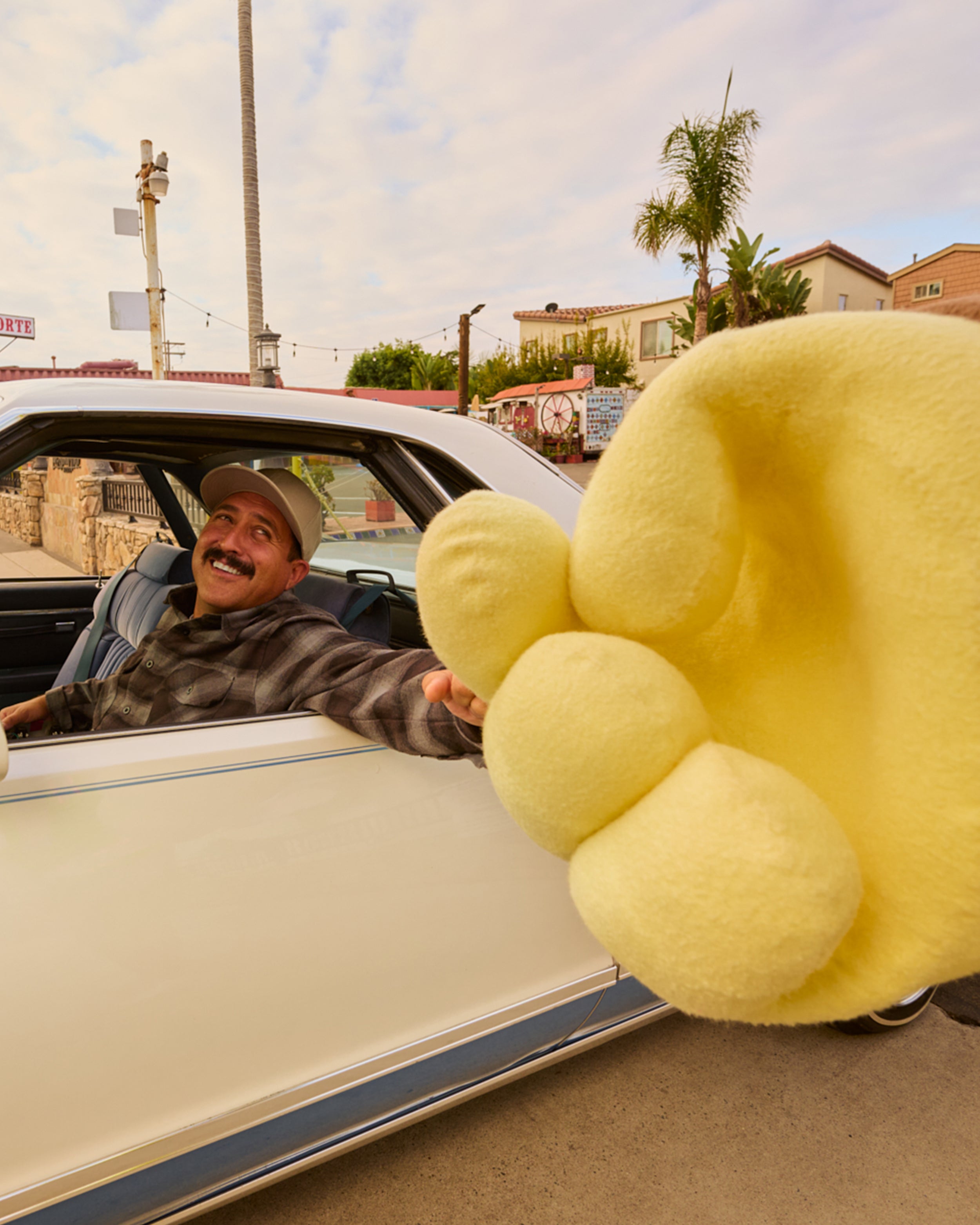 Person in a car with a large yellow paw-shaped object in the foreground