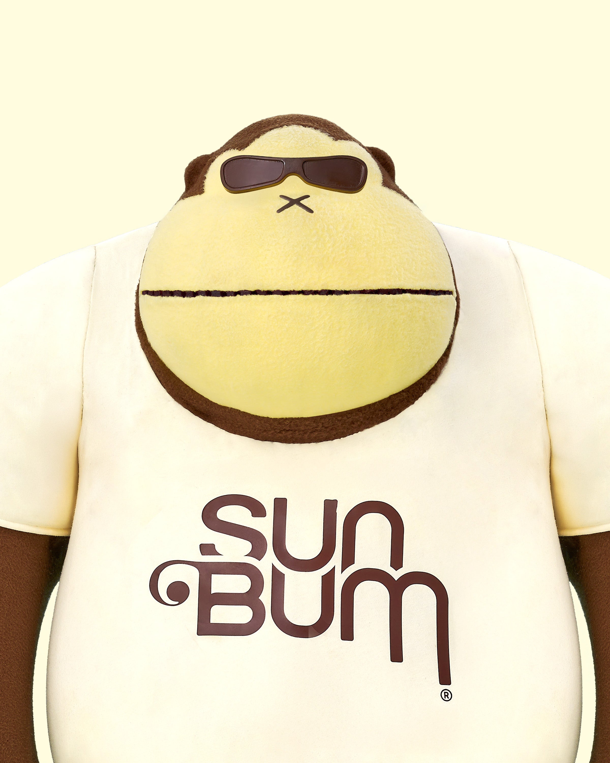 Plush monkey toy with sunglasses and 'Sun Bum' t-shirt on a beige background
