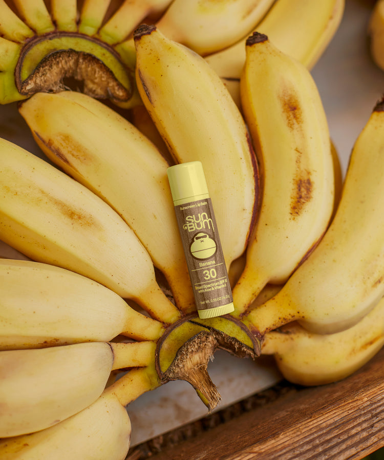 Bottle of Sun Bum sunscreen with bananas on a wooden surface