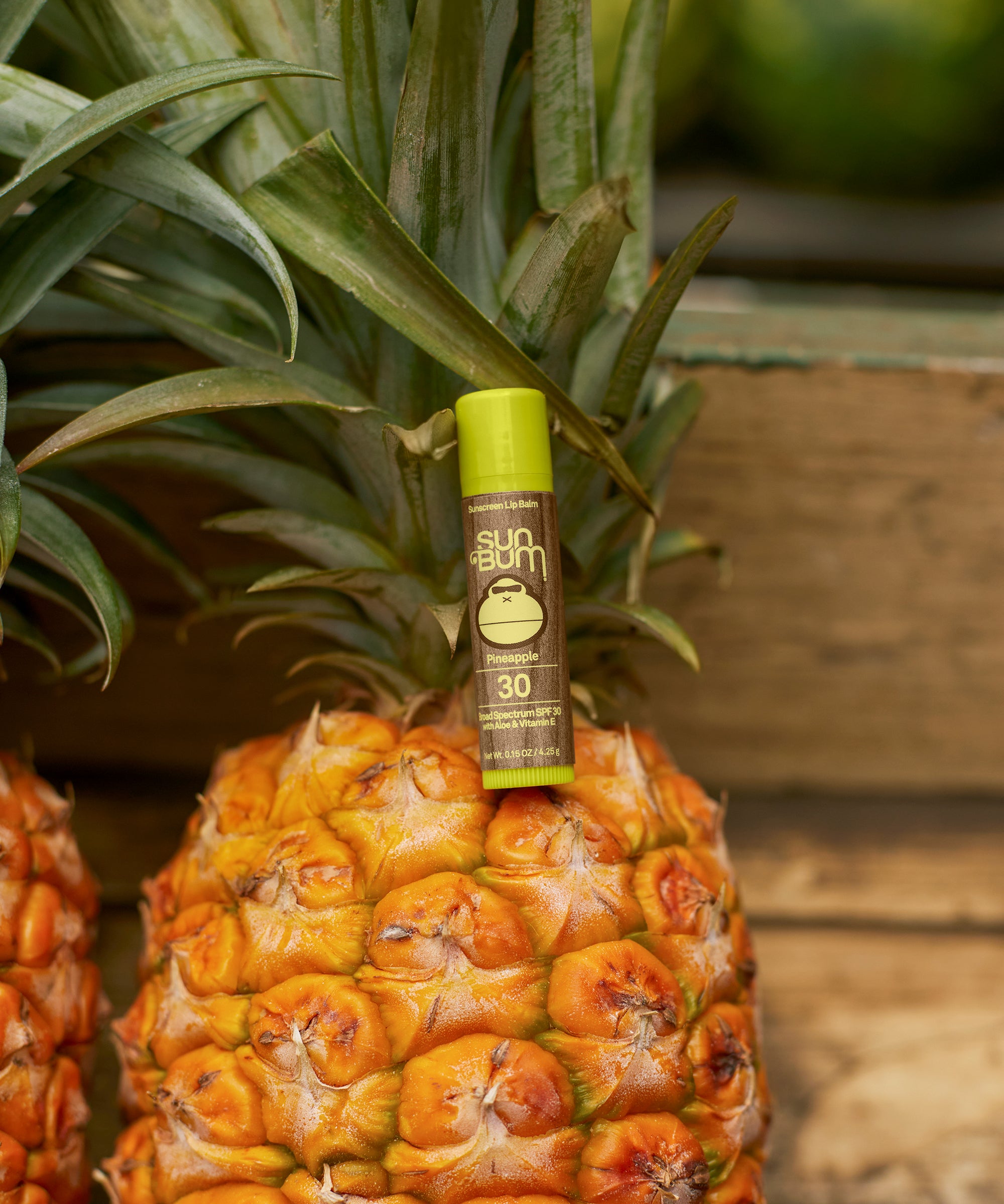 Pineapple with a bottle of alcohol on top, set against a wooden background