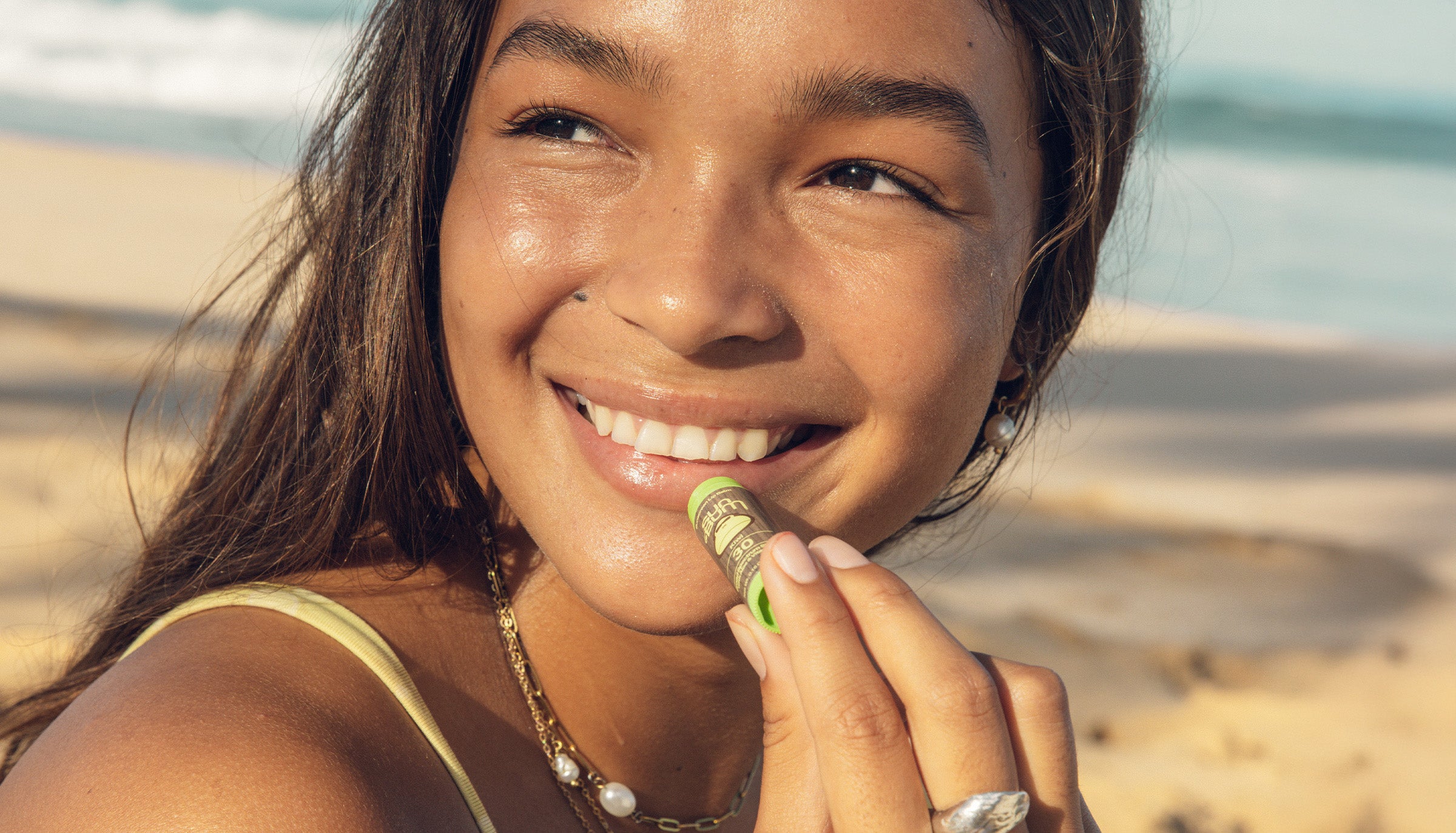Woman eating a snack on a beach with ocean in the background