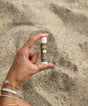 Hand holding a sunscreen stick against a sandy background