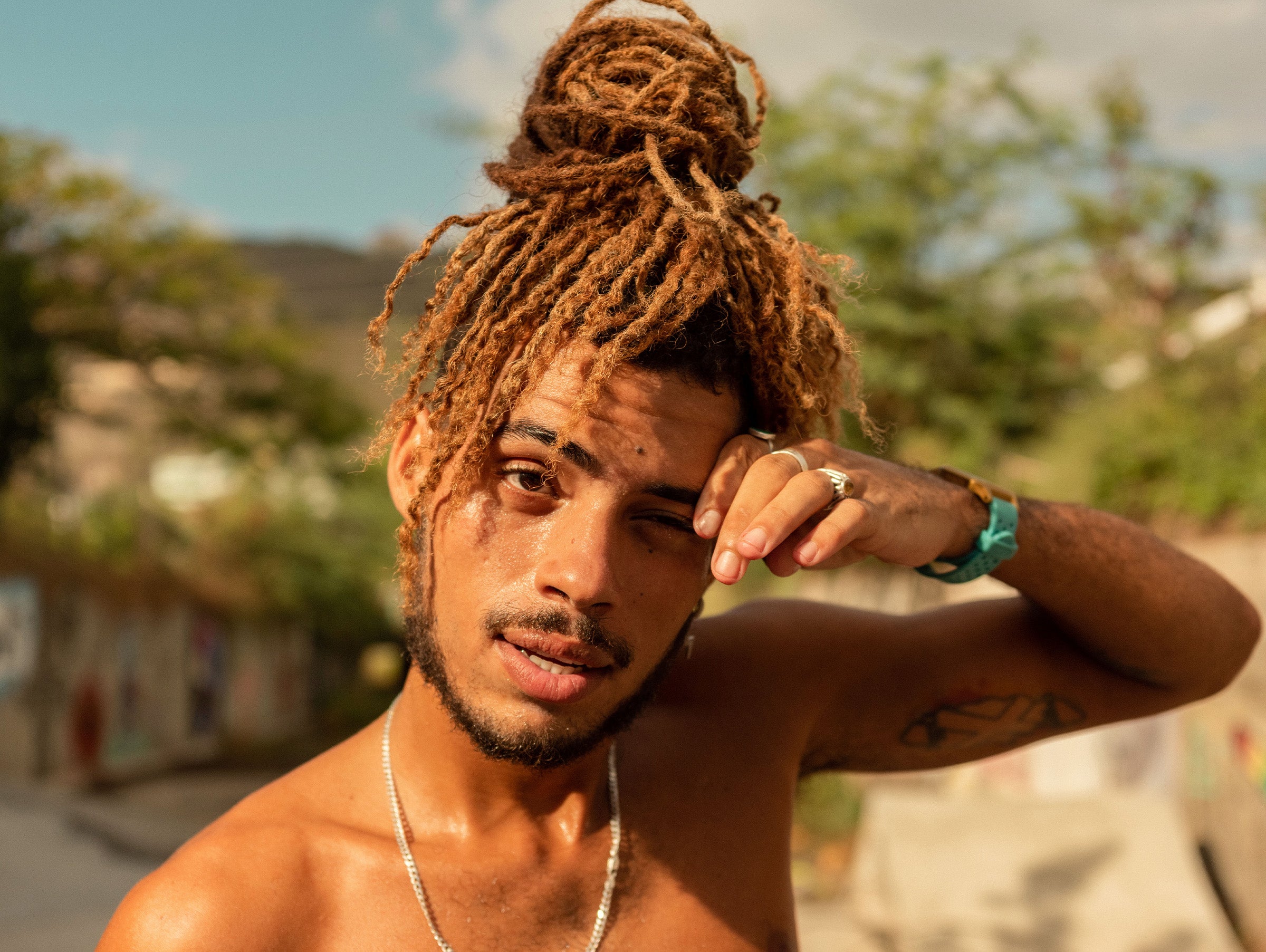 Man with dreadlocks outdoors with a blurred natural background