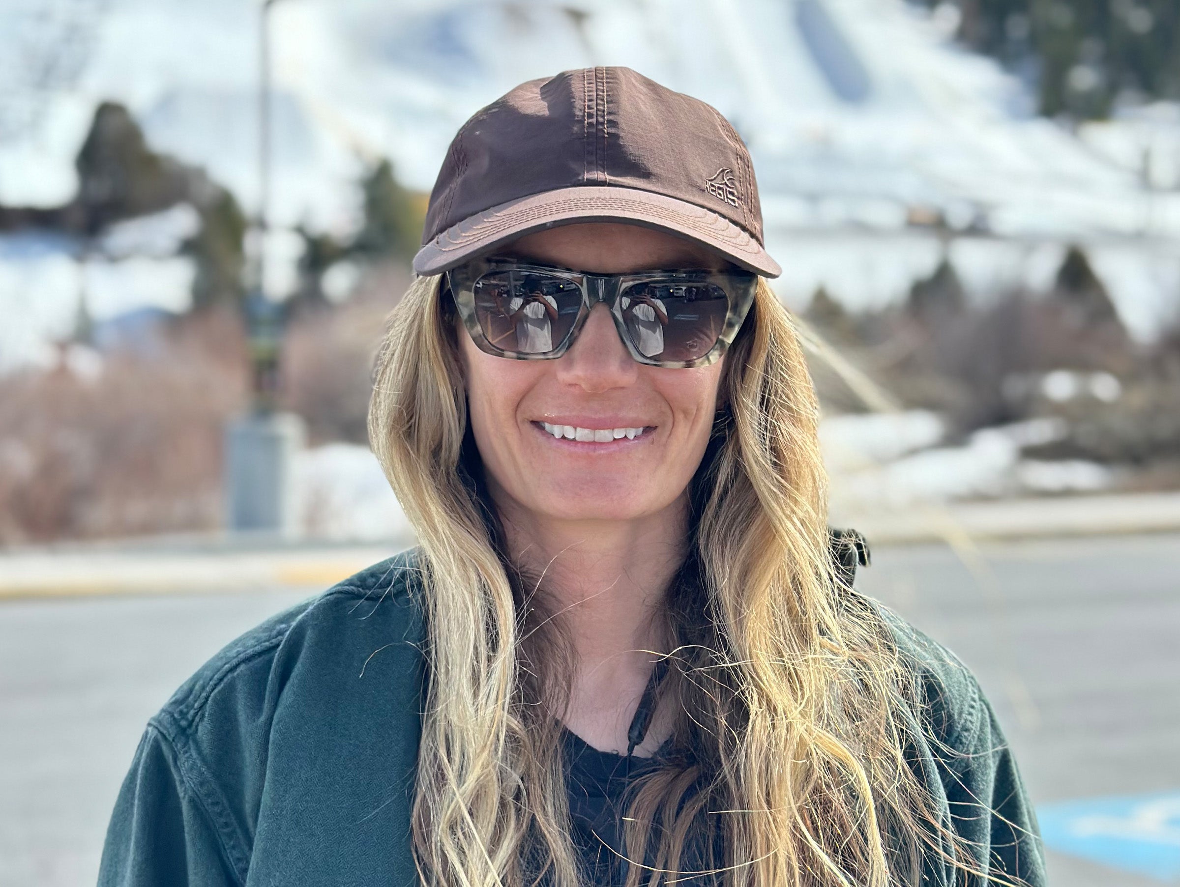 Woman wearing sunglasses and a cap with a snowy landscape in the background