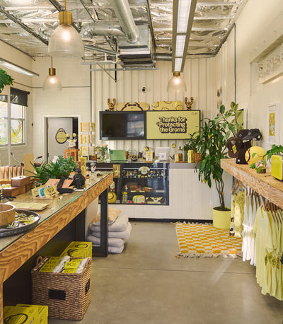 Store interior with wooden counters, plants, and promotional signs.