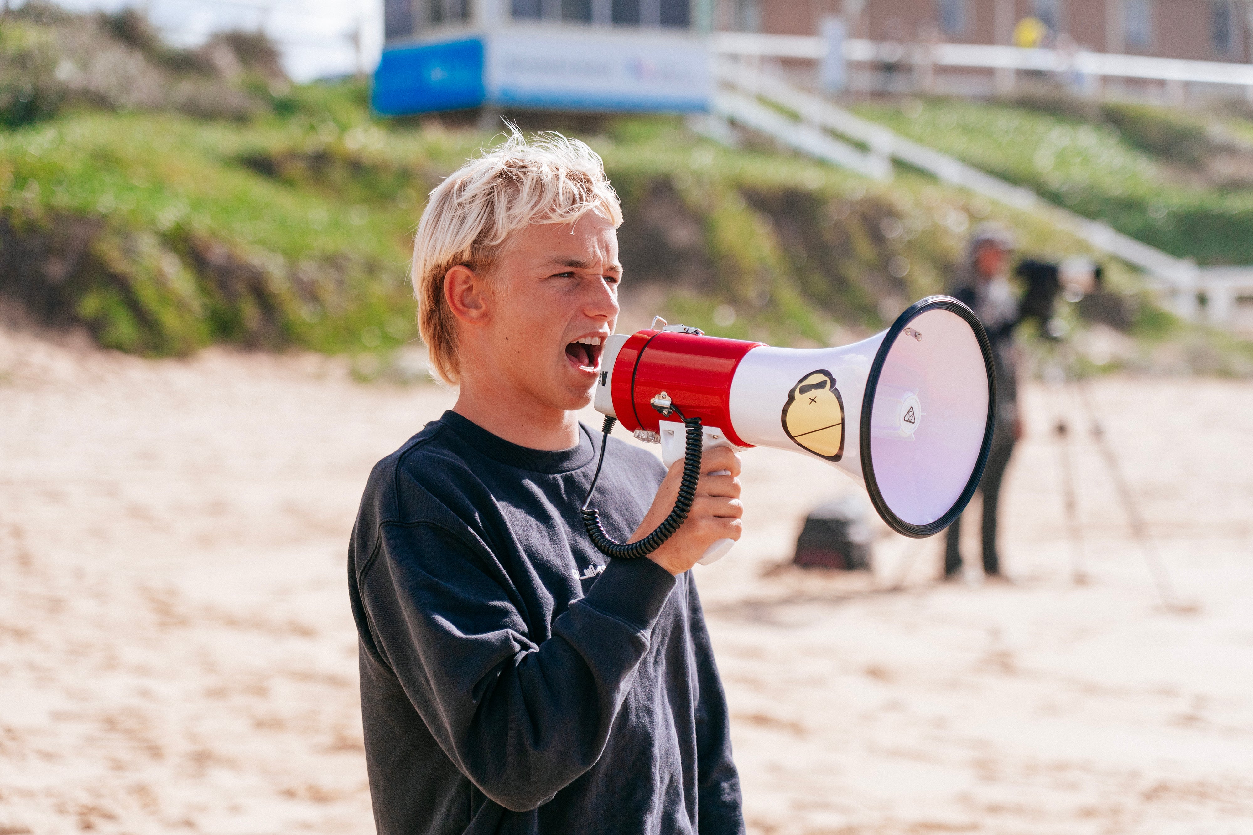 Person holding a megaphone on a beach with a blurred background