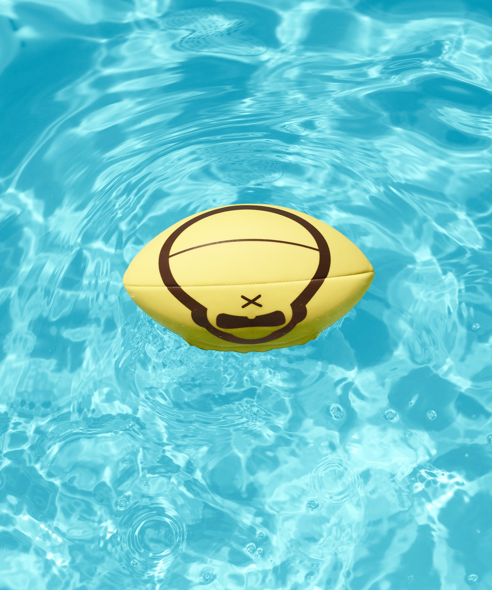 Yellow rugby ball with a black design floating in clear blue water